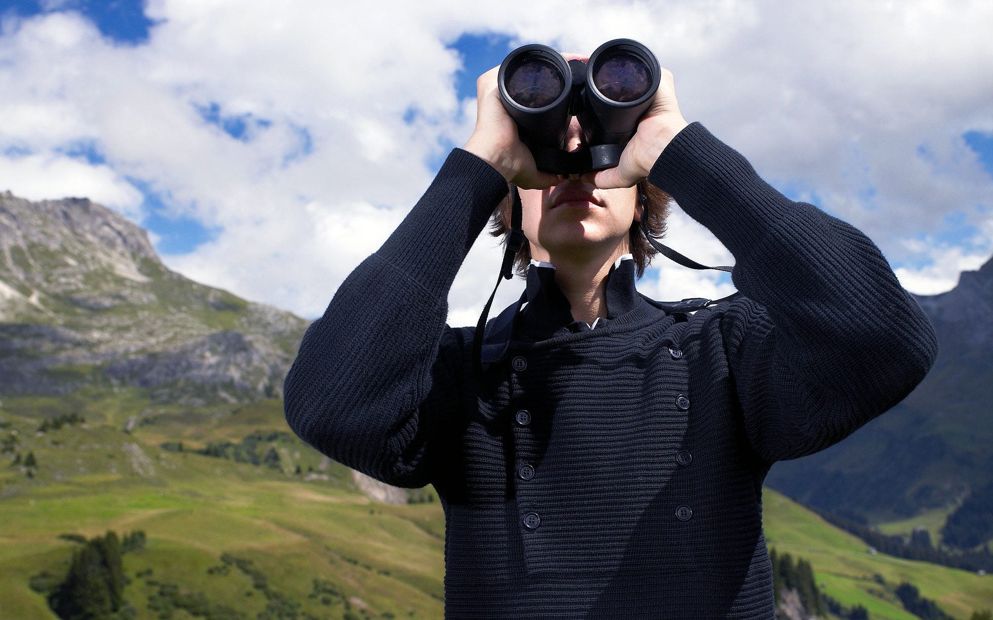 Person using binoculars on hillside