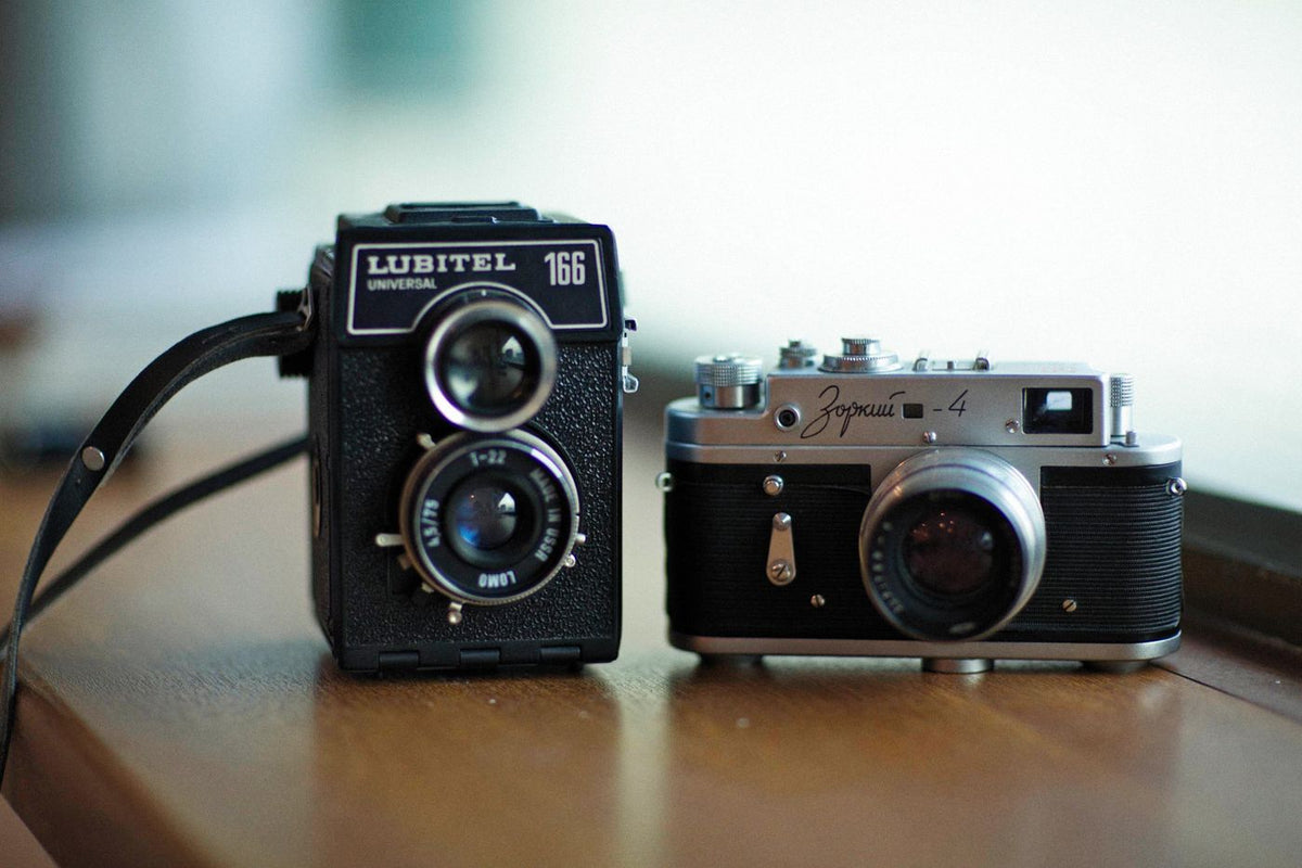 A Lubitel 166 twin-lens camera and a Zorki-4 rangefinder side by side on a wooden shelf