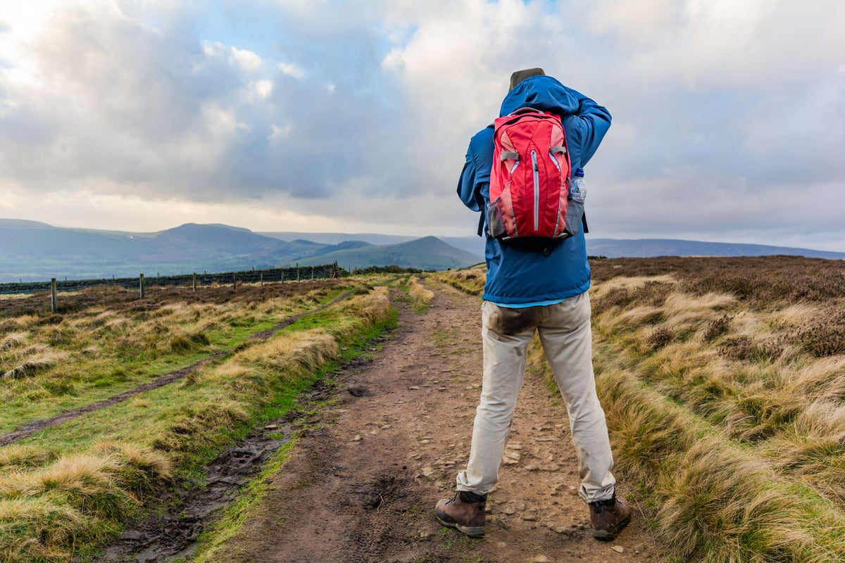 A walker photographing the view along a moorland track in the Peak District